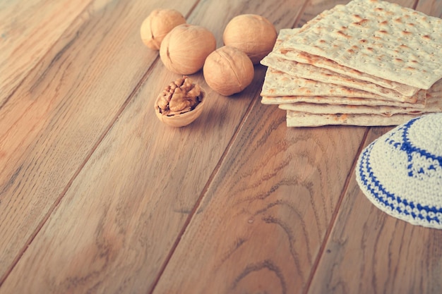 Pessach-Feier-Konzept Matza rot koscher und Walnuss Traditionelles Ritual jüdisches Brot Matza Kippah und Tallit auf altem Holzhintergrund Pessach-Essen Pessach jüdischer Feiertag Getöntes Bild