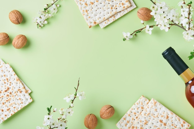 Pessach-Feier-Konzept Matza roter koscherer Wein Walnuss und Frühling schöner Zweig der Kirsche oder des Apfels in voller Blüte Traditionelles jüdisches Brot auf hellgrünem Hintergrund Jüdischer Feiertag Pessach