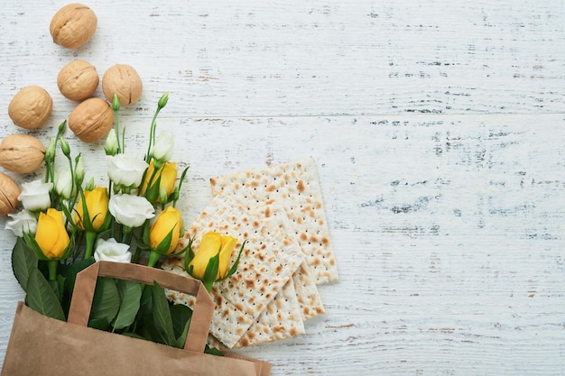 Pessach-Feier-Konzept Matzah koscherer Rotwein Walnuss und weiße und gelbe Rosen Traditionelles rituelles jüdisches Brot auf sandfarbenem altem Kachelwandhintergrund Pessach Jüdischer Feiertag Draufsicht