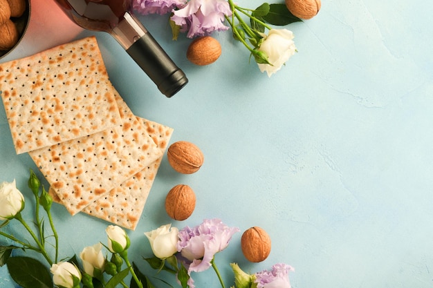 Pessach-Feier-Konzept Matzah rote koschere Walnuss und schöne Rosenblumen im Frühling Traditionelles Ritual jüdisches Brot auf helltürkisem oder blauem Hintergrund Pessach-Essen Jüdischer Feiertag Pessach