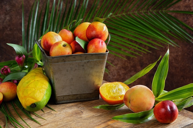 pêssego e manga frescos e deliciosos na cesta de metal. Ingredientes para um smoothie de frutas tropicais