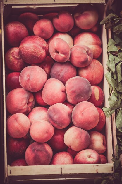 Pêssegos frescos à venda em um mercado. Foto filtrada vertical com foco seletivo