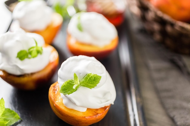 Pêssegos orgânicos grelhados com chantilly e guarnecidos com hortelã fresca.