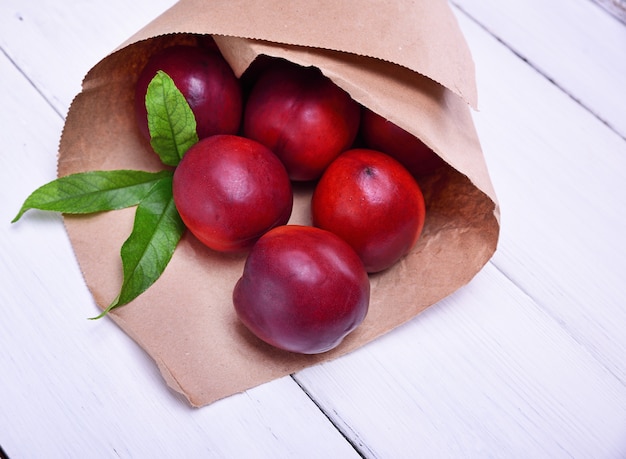 Pêssegos vermelhos maduros em um saco de papel