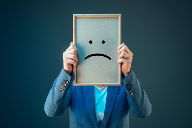 Pessimistische Geschäftsfrau mit einem Smiley-Emoticon über dem Gesicht