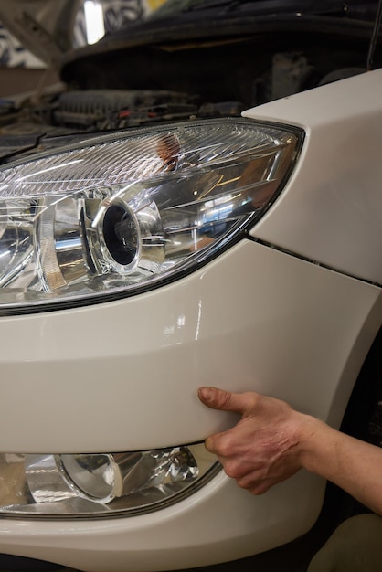 Pessoa a fixar o farol numa garagem com iluminação e ferramentas automotivas