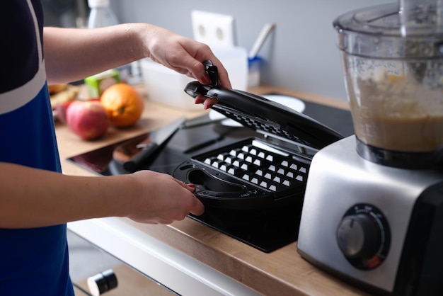 Pessoa abre ferro de waffle elétrico na cozinha