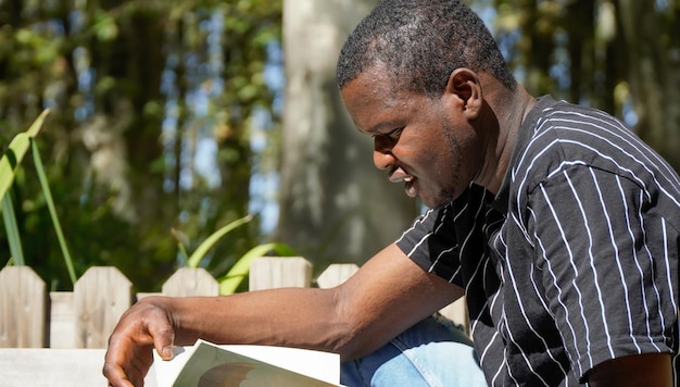 Pessoa africana lendo um livro do lado de fora do homem negro lendo