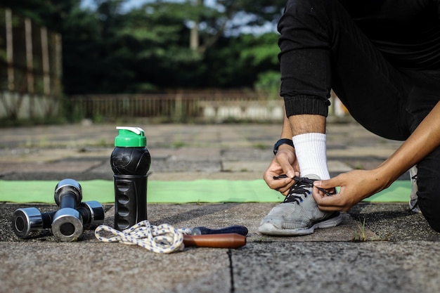 Pessoa amarrando os sapatos se preparando para rotinas de treino de exercícios