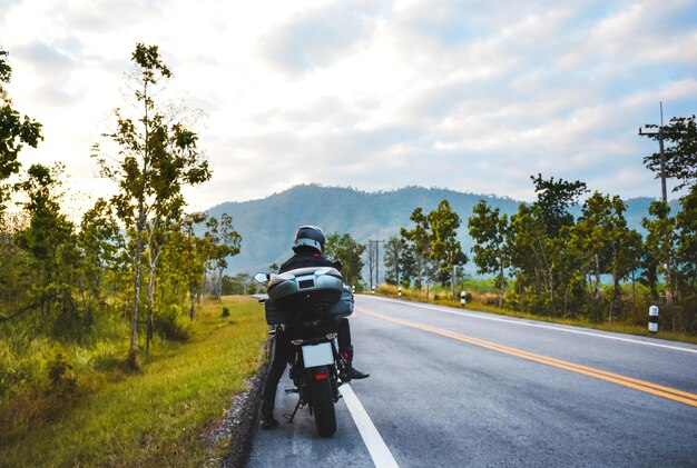 Foto pessoa andando de motocicleta na estrada contra o céu