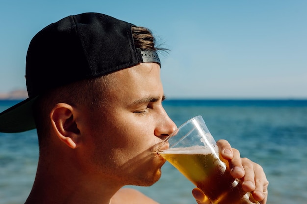 Pessoa bebendo um copo de cerveja no mar retrato homem bebendo cerveja no verão