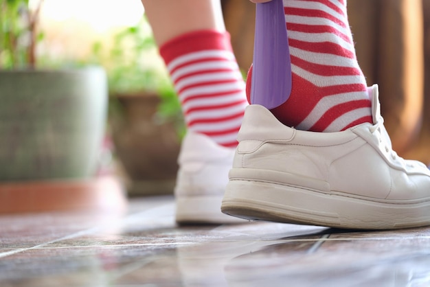 Pessoa coloca sapatos de tênis branco usando calçadeira