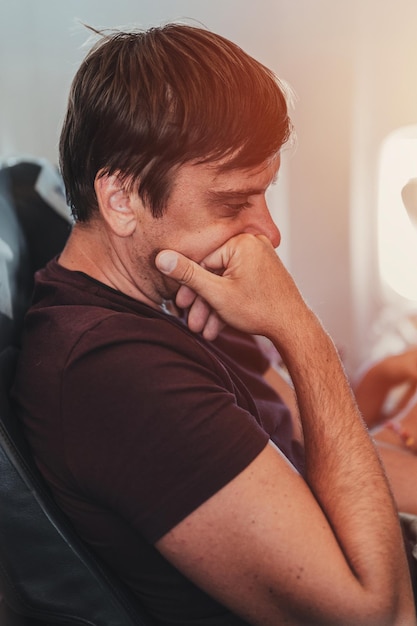 Pessoa com barba pensativa entediada homem com 40 anos com barba por fazer está sentado em um avião durante um voo do aeroporto para viajar passando tempo no avião ocioso e não fazer nada flare