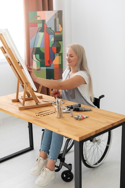 Foto pessoa com deficiência em cadeira de rodas pintando