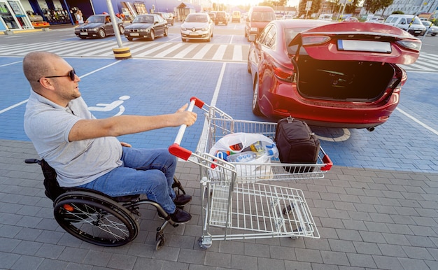 Foto pessoa com deficiência física coloca as compras no porta-malas de um carro no estacionamento de um supermercado