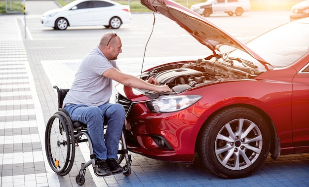 Pessoa com deficiência física verifica o motor do carro no estacionamento