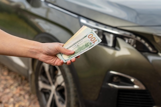 Pessoa com dinheiro na mão fica na frente do carro Empréstimo de seguro e compra do conceito de carro