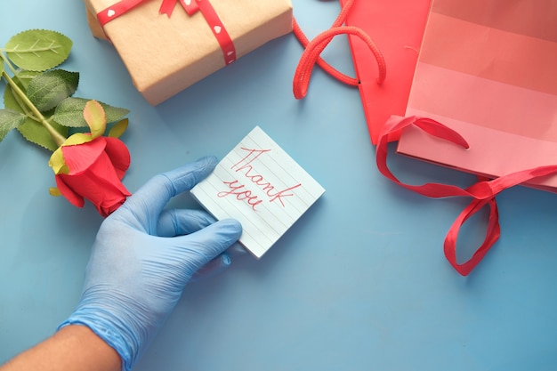 Pessoa com luvas de látex segurando uma carta de agradecimento