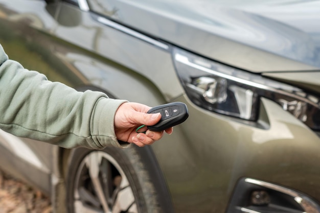 Pessoa com uma chave de carro na mão fica na frente do carro Empréstimo de seguro e compra do conceito de carro