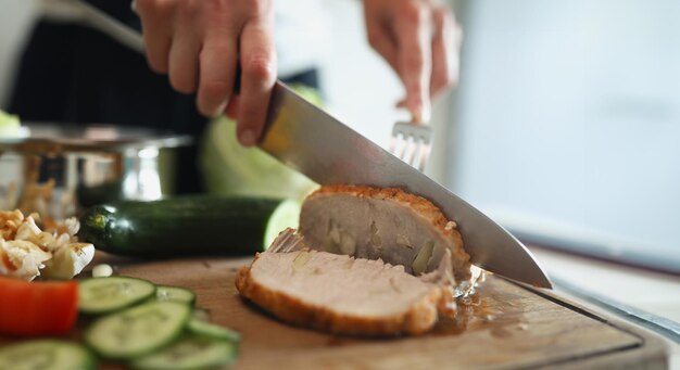 Foto pessoa cortando presunto caseiro deliciosa carne aromática com pedaços de alho