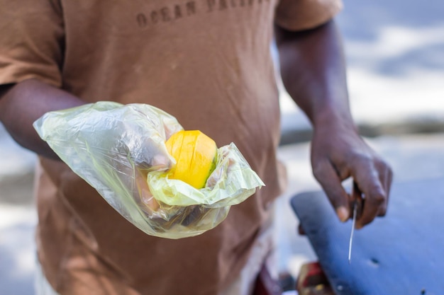 Pessoa de cor escura cortando frutas para clientes em sua estação de trabalho