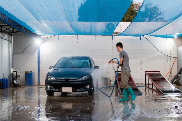 Pessoa de costas lavando um carro com uma mangueira em um lavador de carros