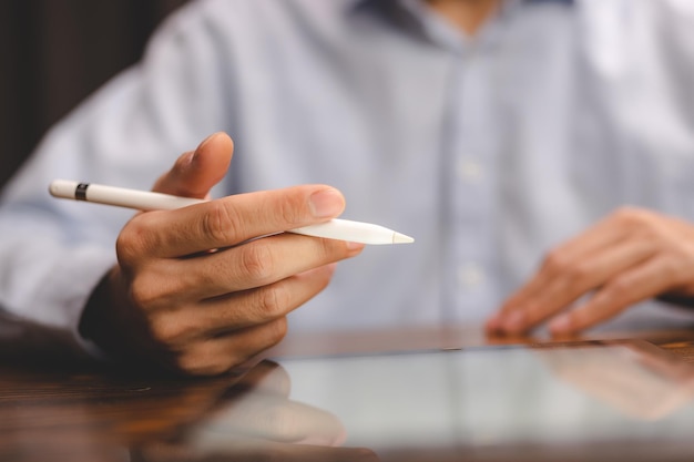 Foto pessoa de empresário de conceito de tecnologia de comunicação empresarial usando caneta digital para trabalhar no dispositivo de tela do computador tablet no documento de marketing on-line do local de trabalho de escritório moderno na mesa de mesa