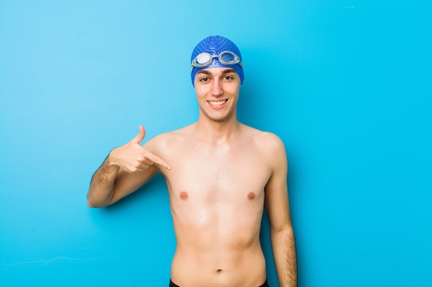 Pessoa de homem jovem nadador apontando à mão para um espaço de cópia de camisa, orgulhoso e confiante