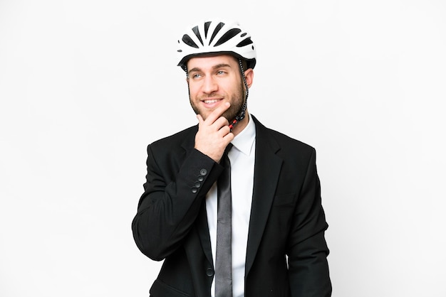 Pessoa de negócios com um capacete de bicicleta sobre fundo branco isolado, pensando em uma ideia enquanto olha para cima