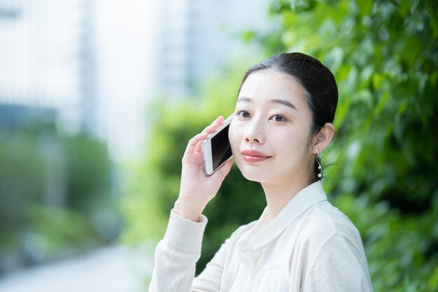 Pessoa de negócios feminino asiático entrando em contato usando um martphone ao ar livre