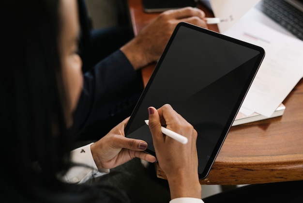 Pessoa de negócios usando uma caneta sem fio com um tablet digital em uma reunião