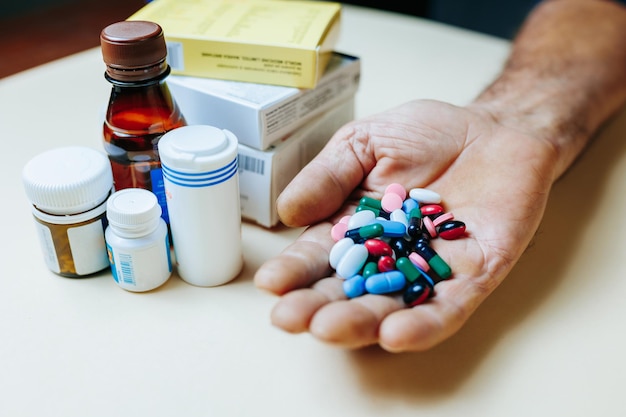 Pessoa de perto segura comprimidos nas mãos, medicamentos multicoloridos, muitos comprimidos, grandes doses de medicamentos