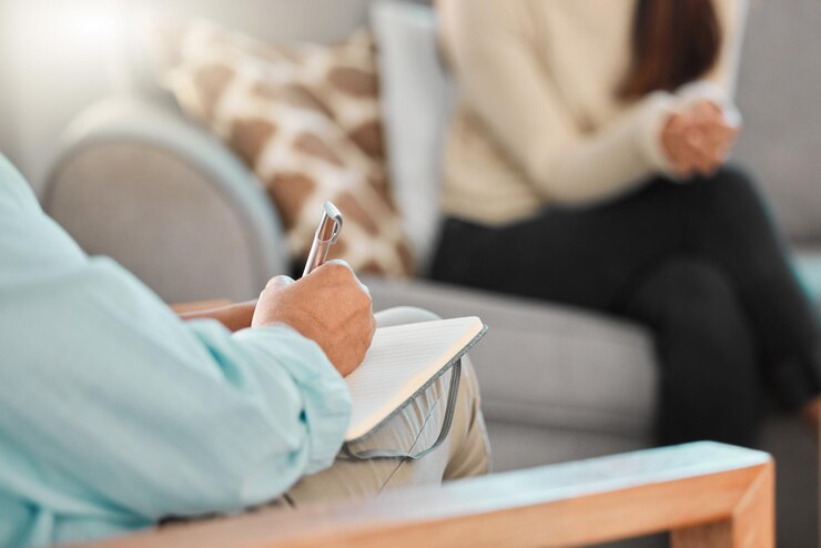 Foto pessoa de sofá e terapeuta com caderno para consulta escrita de anotações e suporte ao cliente para saúde mental terapia paciente e psicólogo com revisão para aconselhamento ouvir e ajudar na sessão