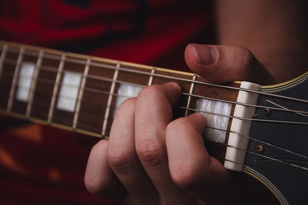 Pessoa dedilhando as cordas nos trastes de uma guitarra elétrica. foco seletivo. copie o espaço.