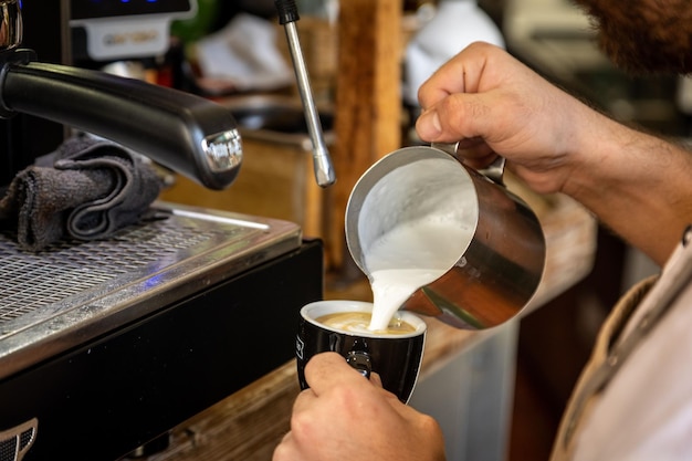 Pessoa derramando leite em uma xícara de café em um café