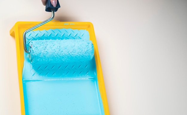 Pessoa desconhecida mergulha rolo em tinta azul rolando na bandeja de plástico Close-up Conceito de trabalho de reparo e melhoria das condições de habitação
