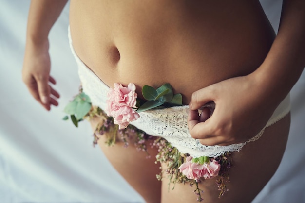 Pessoa e flores em roupas íntimas com cuidados femininos higiene e menstruação saúde para bem-estar Mulher close-up e cravo rosa em calças de ginecologia conforto ecológico e de saúde