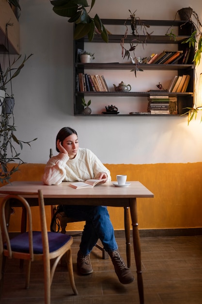 Foto pessoa em um café lendo um livro enquanto toma café