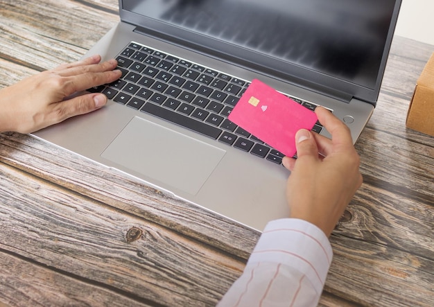 Pessoa fazendo compra online com cartão na mão