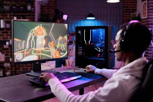 Gamer transmitindo o jogo de tiro em primeira pessoa enquanto explica a  jogabilidade aos assinantes enquanto está sentado na cadeira de jogos.  homem usando a configuração do pc jogando jogo de ação