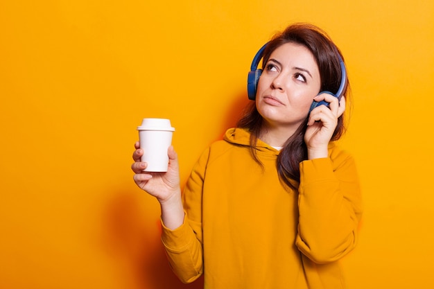 Pessoa feliz com uma xícara de café ouvindo música no fone de ouvido