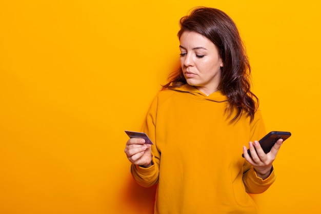 Pessoa feliz usando cartão de crédito para fazer compras online no smartphone