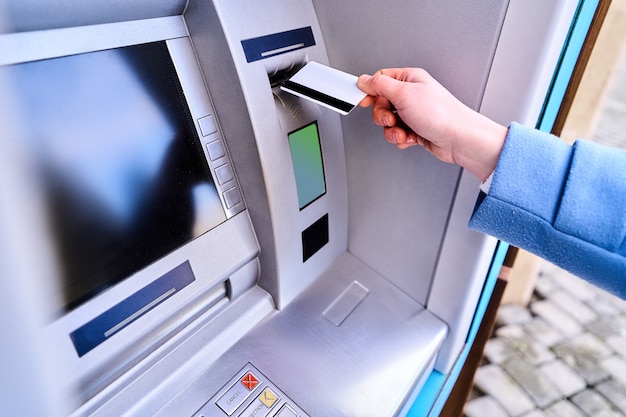 Pessoa inserir cartão de crédito plástico no banco atm para retirar dinheiro