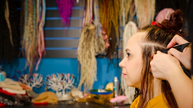 Foto pessoa irreconhecível faz penteado para jovem no salão cabeleireiro profissional faz penteado para cliente