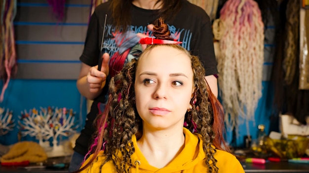 Pessoa irreconhecível faz penteado para jovem no salão Cabeleireiro profissional faz penteado para cliente