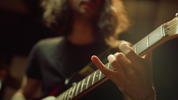 Pessoa irreconhecível tocando guitarra no estúdio Mão de homem beliscando acordes no interior