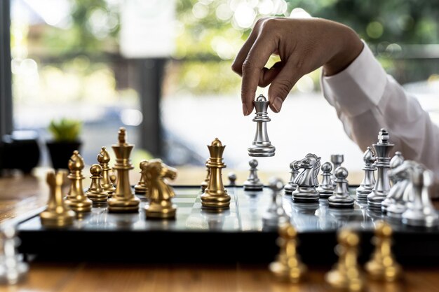 Pessoa jogando jogo de tabuleiro de xadrez, imagem de conceito de mulher de negócios segurando peças de xadrez como competição de negócios e gerenciamento de riscos, planejando estratégias de negócios para derrotar concorrentes de negócios.