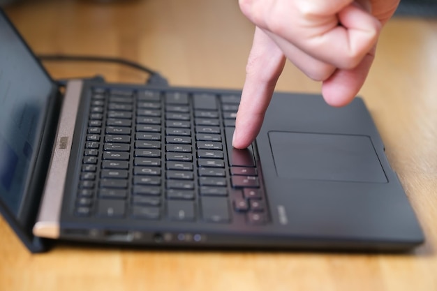 Pessoa pressiona botões no teclado do laptop com dois dedos