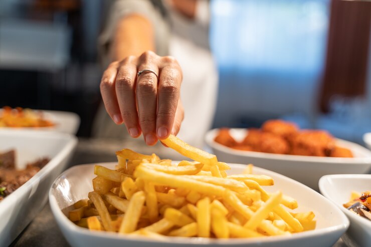 Pessoa que toma uma batata de um prato de batatas fritas em um restaurante