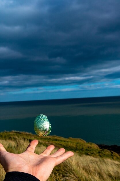 Foto pessoa segurando a bola no mar contra o céu